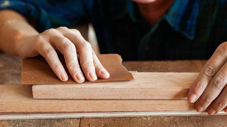 Person sanding a plank of wood