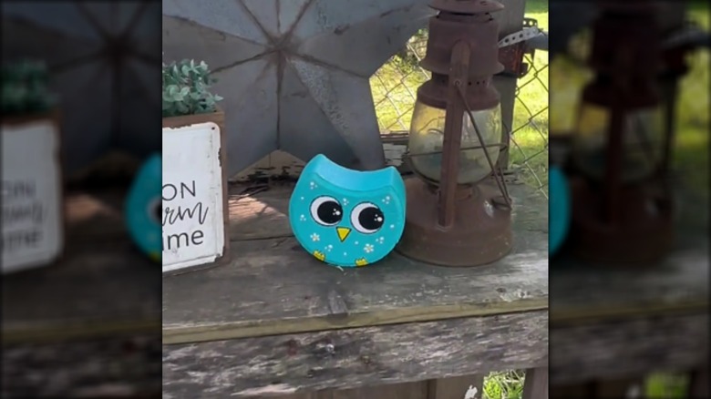 Rounded paver painted to look like an owl sitting on a bench