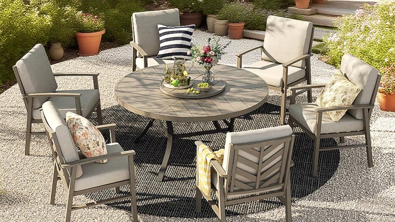 Six gray chairs sit around a round patio table