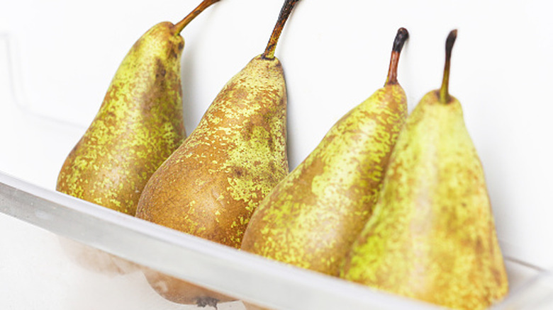 Four pears stored in a refrigerator shelf