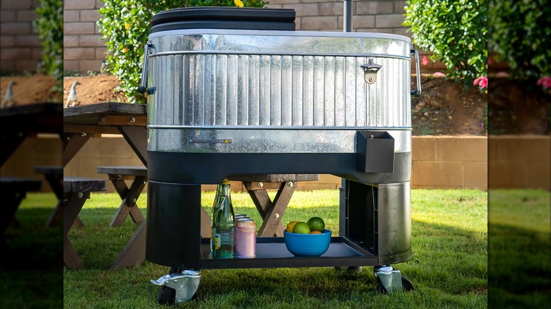 A large stainless steel Permasteel rolling cooler sits on a grassy lawn