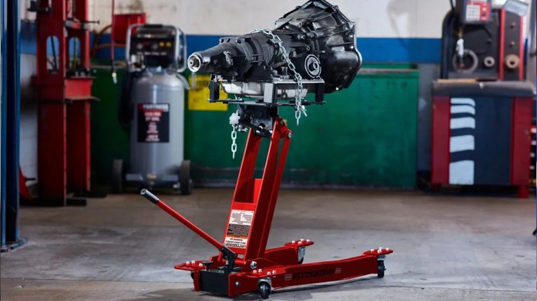 Mechanic using floor jack to lift car