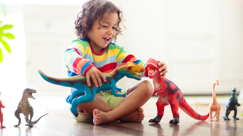 A little boy is playing with dinosaur figurines