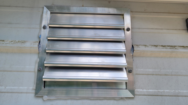 An aluminum 12-inch vent in the wall of a metal workshop
