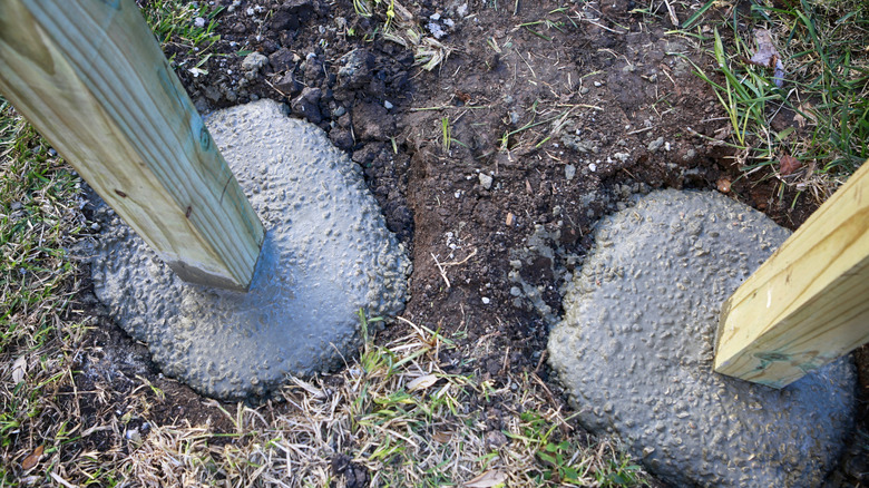 Wooden fence posts setting in wet concrete