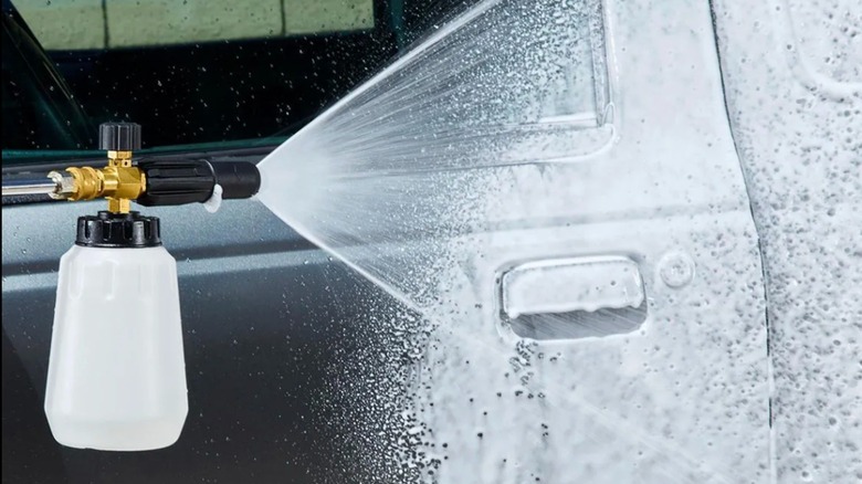 Person washing car with a foam cannon attached to a garden hose