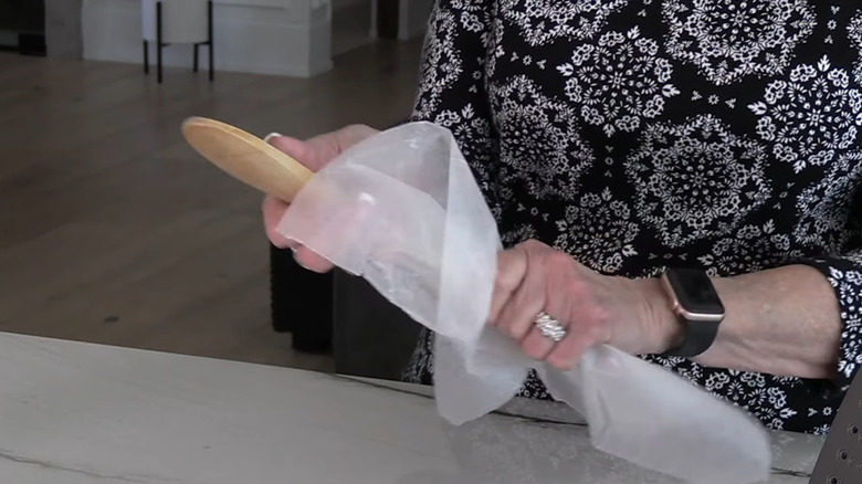 Woman's hands wiping wooden spoon with sheet of wax paper