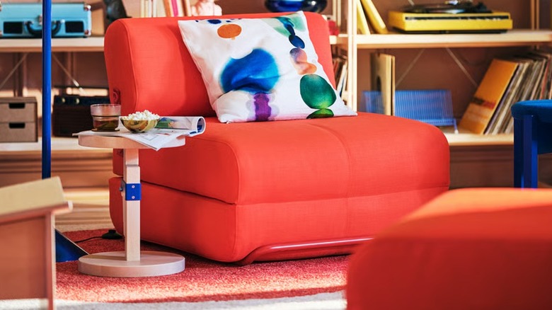 A chunky, bright orange chair with a colorful cushion on top