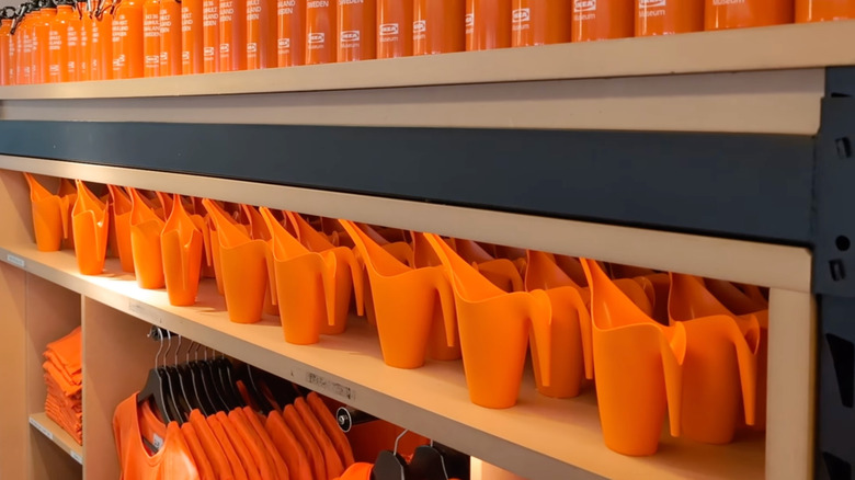 Orange miniature watering cans are displayed on a shelf at the IKEA Museum shop