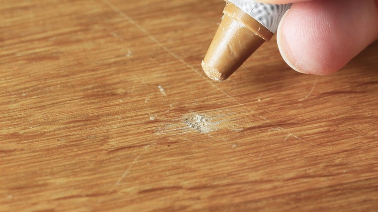 Person filling nick in wood with a putty stick