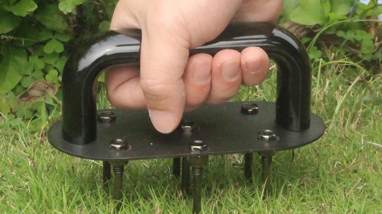 Person pressing the Qsxou Hand Aerator into the ground