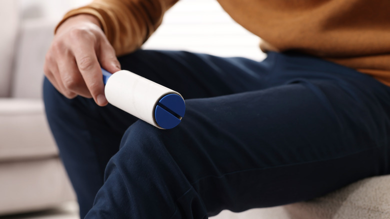 man rolling off clothes with lint roller
