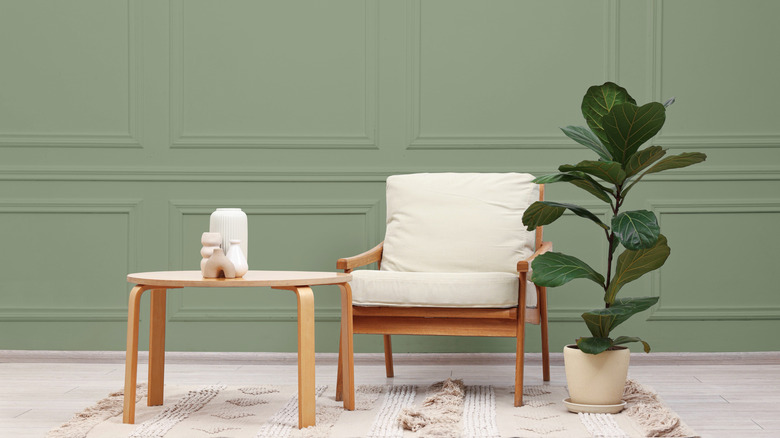An armchair and table in front of a soft sage green wall