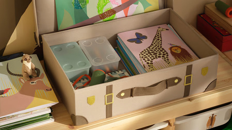 A light brown SANDLÖPARE Storage trunk from IKEA is filled with arts and crafts supplies