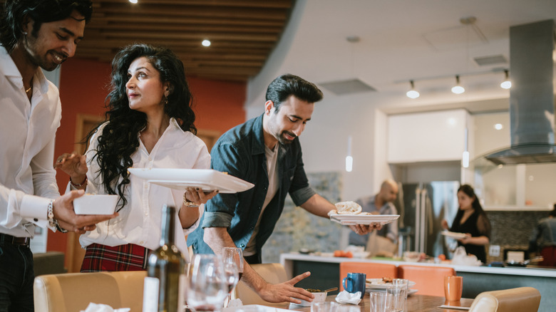 Friends collecting dishes after a dinner party