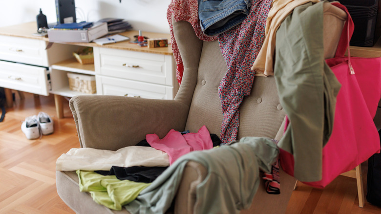 Messy room with a a laundry chair piled with clothes