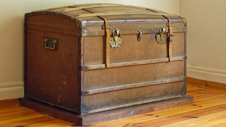 An old wooden trunk sits in the corner of a plain room