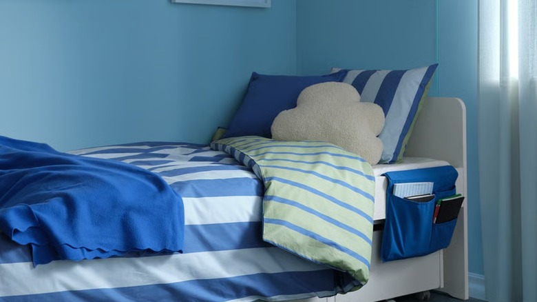 A blue STICKAT bed pocket hanging off a small bed