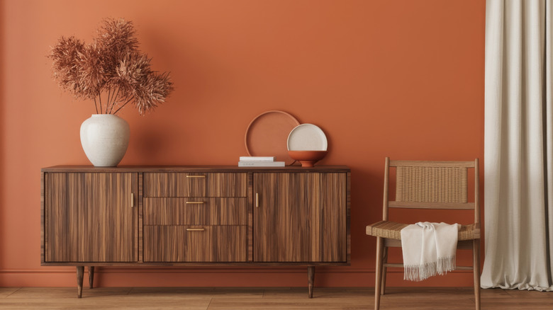 Terracotta walls behind a living room sideboard and chair