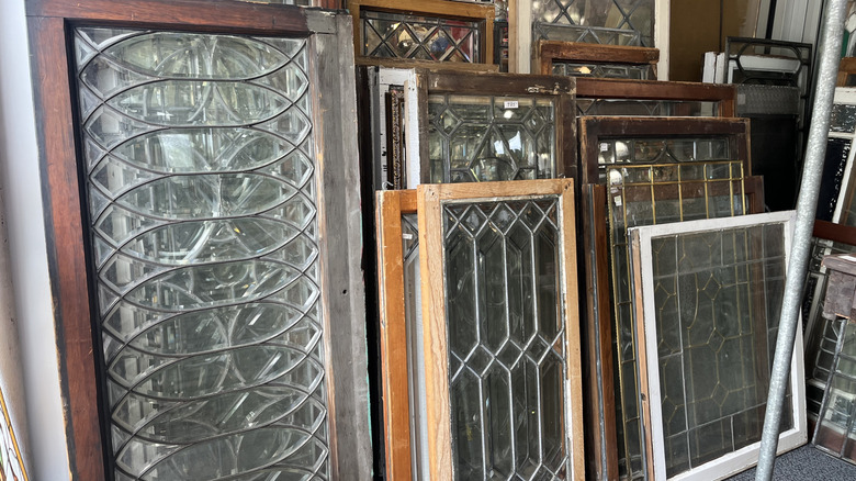 A display of stacked vintage leaded window panels at architectural salvage shop