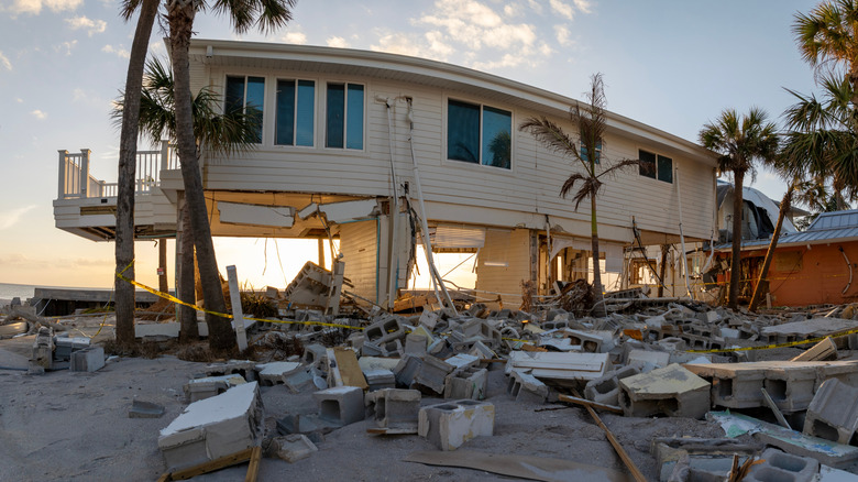 Storm-damaged home with debris around it