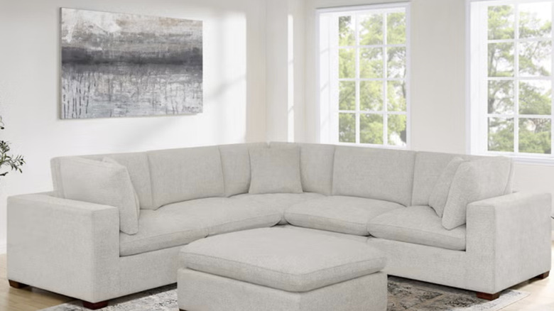A white six-piece sectional in a white living room against the wall and window