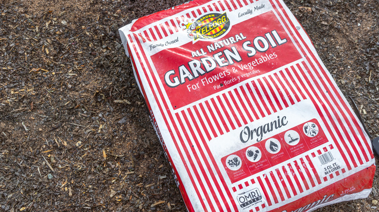 A red striped bag of Kellogg Garden Organics Garden Soil lays on the ground.