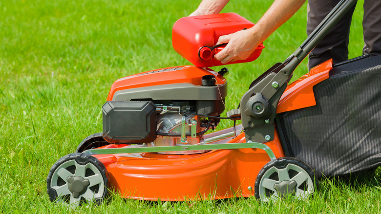 hands pouring fuel into lawn mower