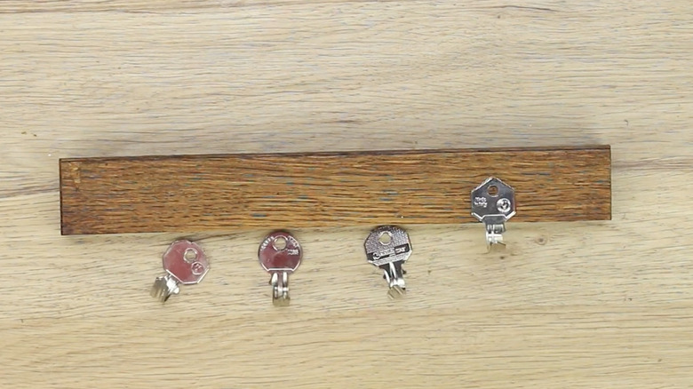 Small wood plank with a collection of bent key hooks next to it