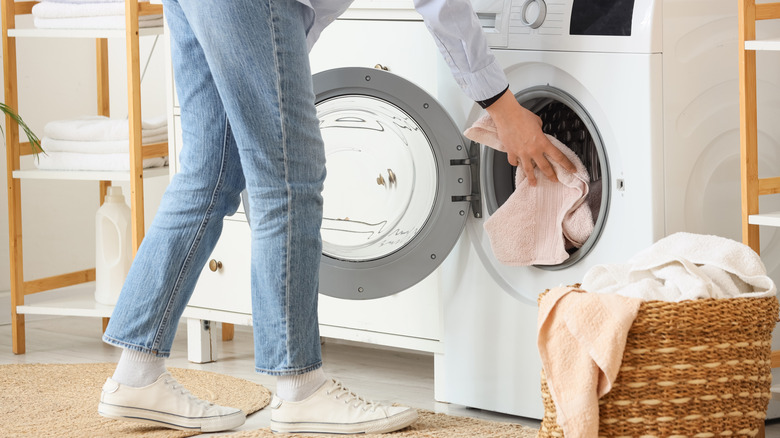 A woman loading dirty clothes in a washer