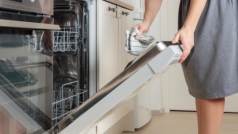 Woman using a cloth to wipe a dishwasher door