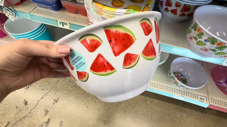 a hand holding a white bowl with watermelons printed on it