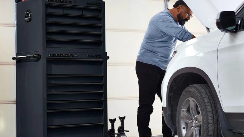 Mechanic working on car wioth roll cab to the side