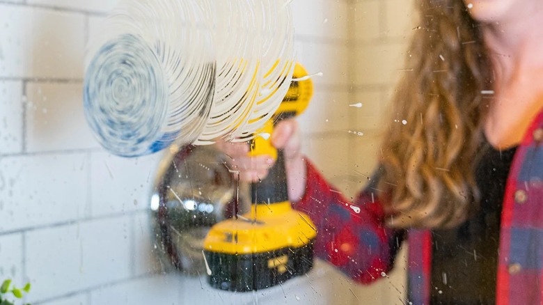 Woman using drill and RotoScrub Bathroom Cleaning Scrub Pad to clean glass shower door