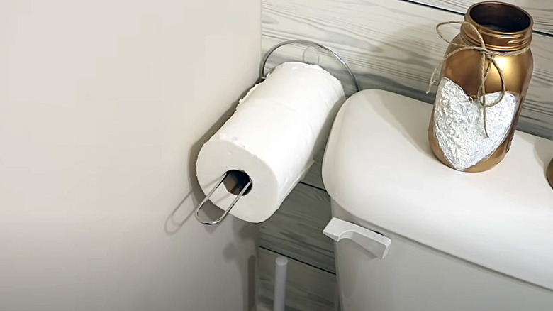 Rolls of toilet paper stored on a paper towel holder mounted to the wall next to a toilet.