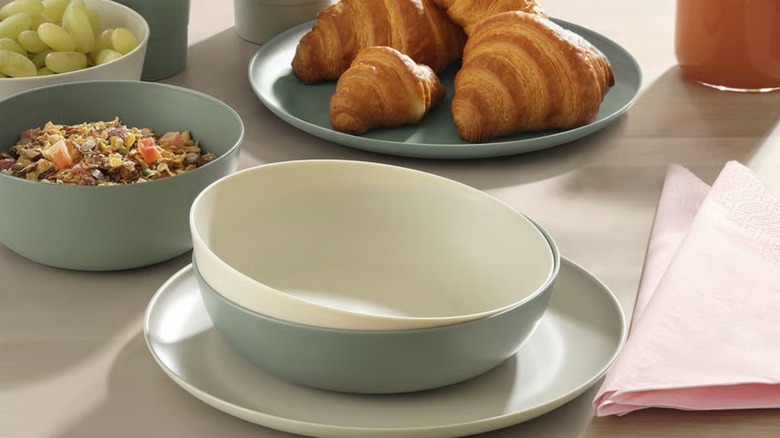 A white VITABBORRE deep bowl nestled within a green deep bowl on a dinner table