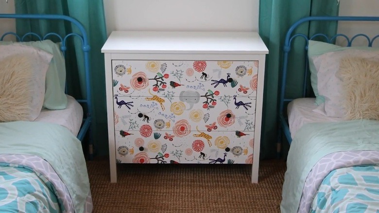 wallpapered dresser between two blue beds