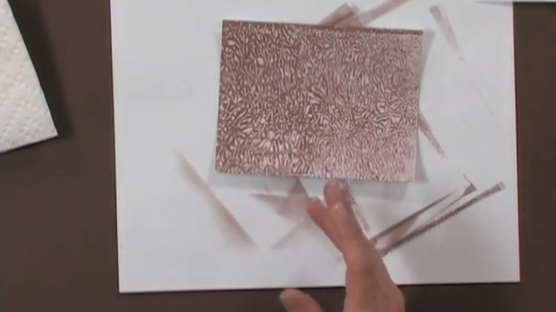 Hand gesturing at a resist print made using wax paper