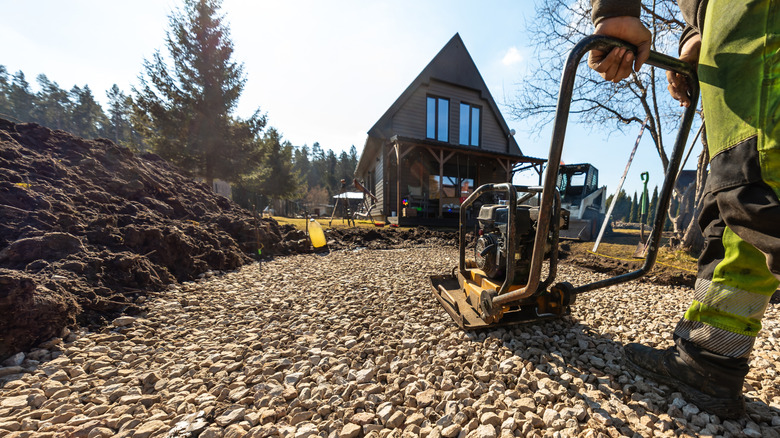 a worker compacting a sub-base layer of gravel driveway