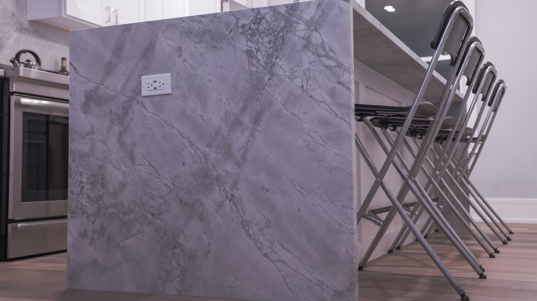 A luxurious waterfall kitchen island with a wide quartzite counter