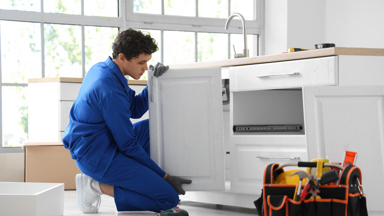 A man replaces a kitchen cabinet door.