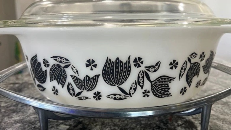 A Pyrex Black Tulip casserole dish with lid and cradle