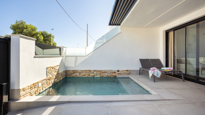 Plunge pool set into concrete backyard of home