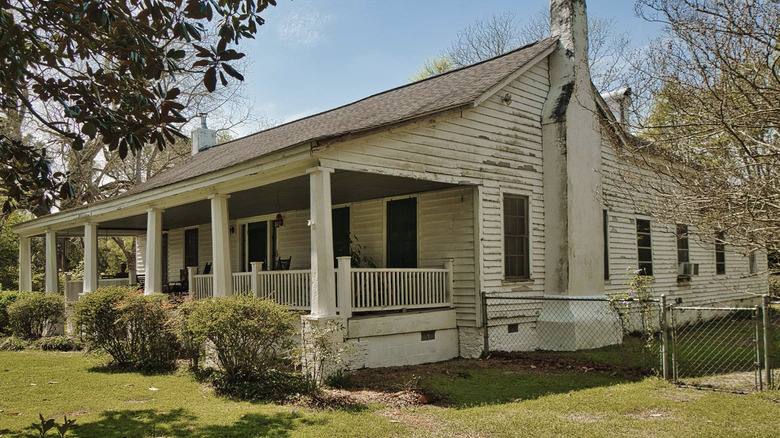 Old white house with rain porch on brick platforms