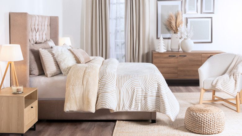 Bed made with a long comforter that drapes down most of the side of the bed