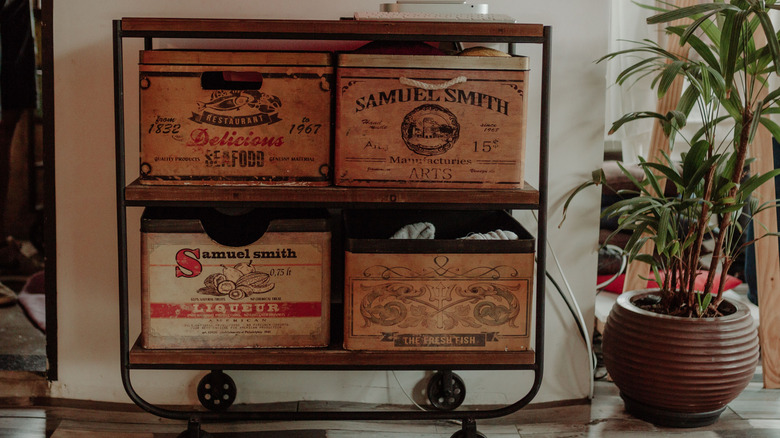 Vintage wooden wine and liquor boxes are stored on a rolling shelf