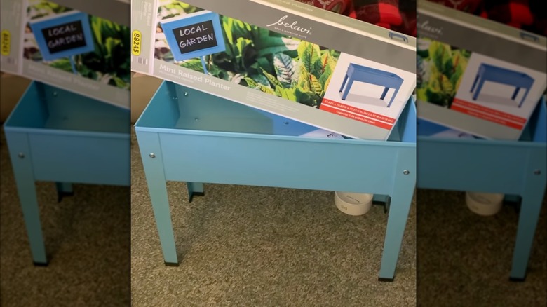 A box sits on top of a fully assembled blue Belavi Raised Bed Planter from Aldi